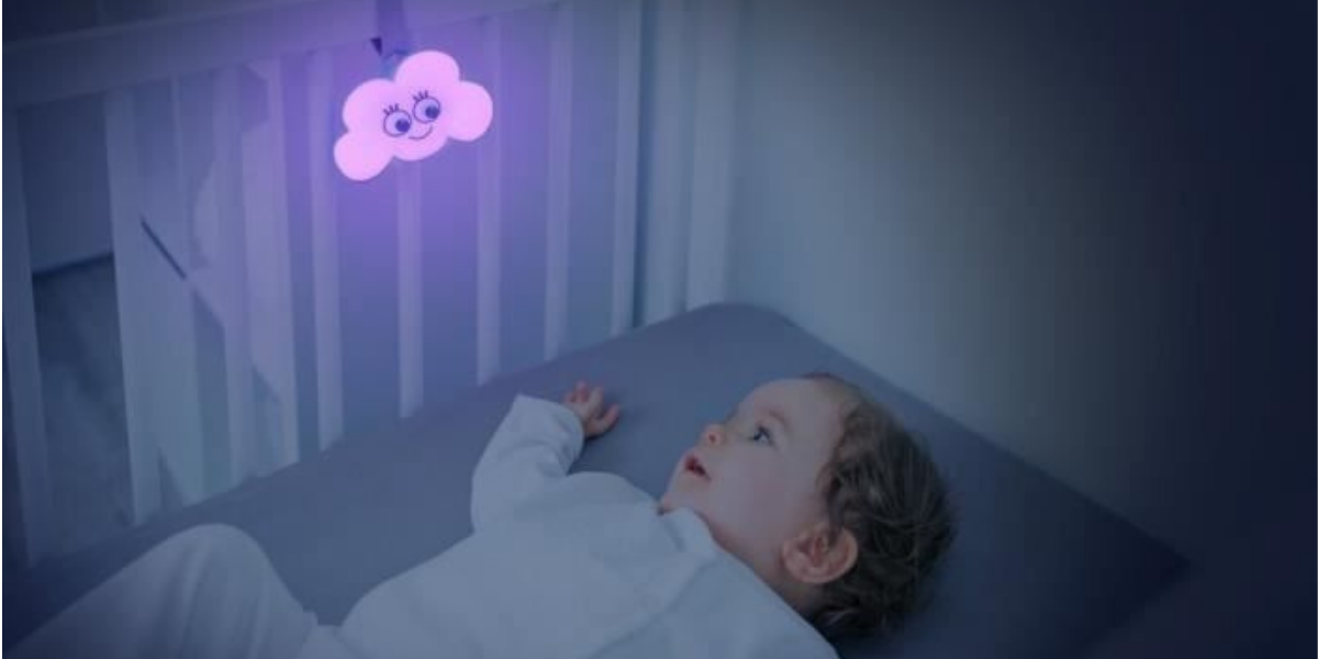 veilleuse nuage accroché barreaux lit bébé. bébé allongé dans le lit et regarde la veilleuse nuage