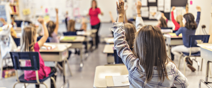 des enfants lèvent le doigt dans une classe d'école
