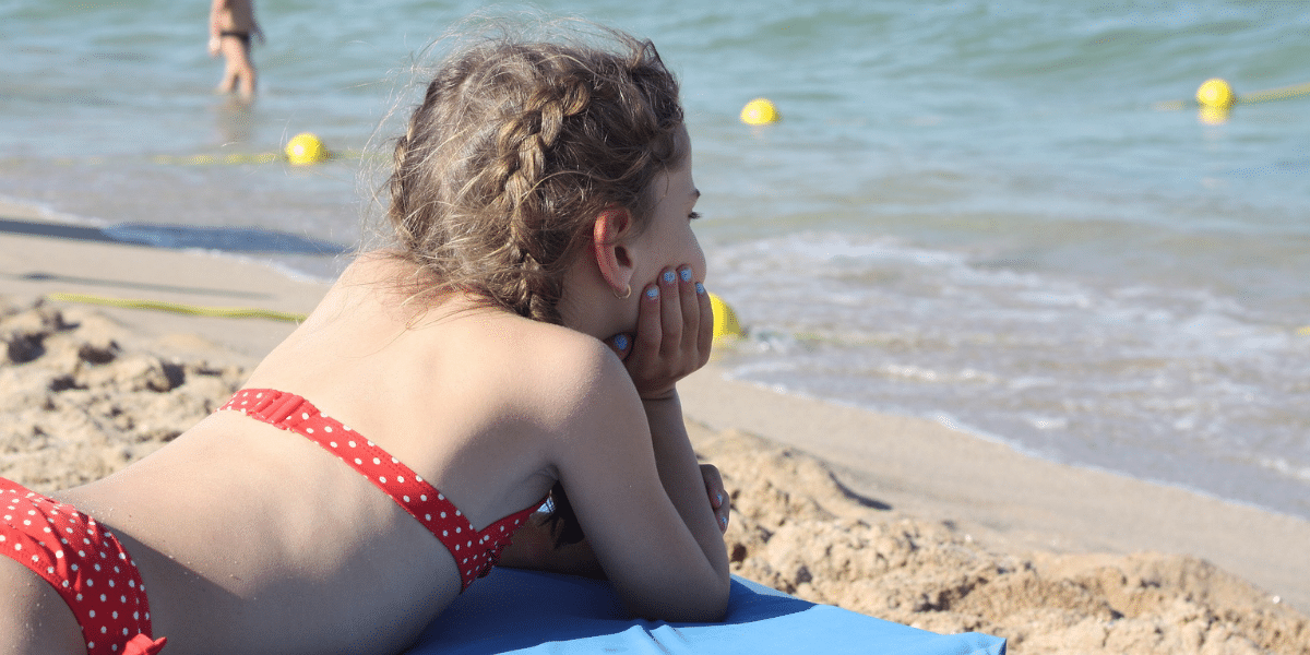 petite fille sur la plage en maillot de bain rouge