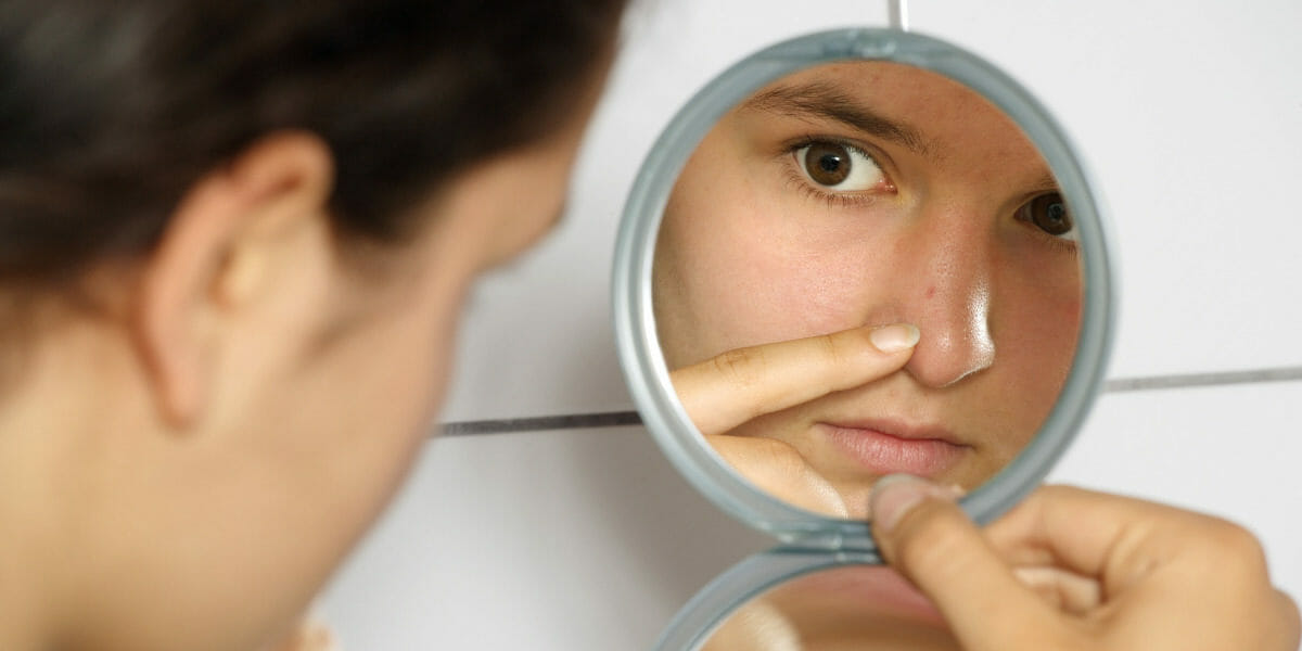 adolescente-qui-se-regarde-dans-un-miroir-avec-poussee-acne